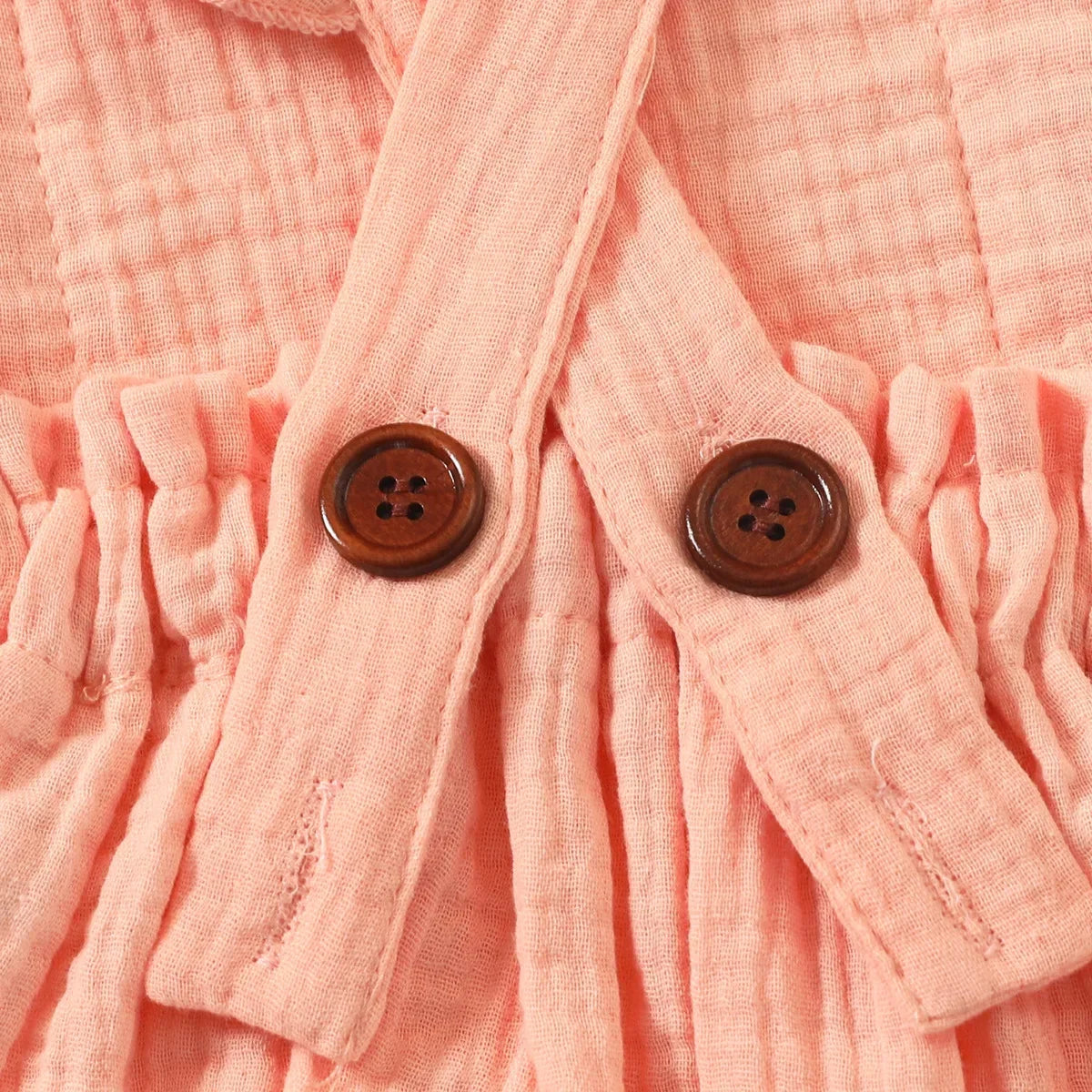 Baksida med knappar närbild på rosa ärmlös romper för nyfödda tjejer med matchande hårband