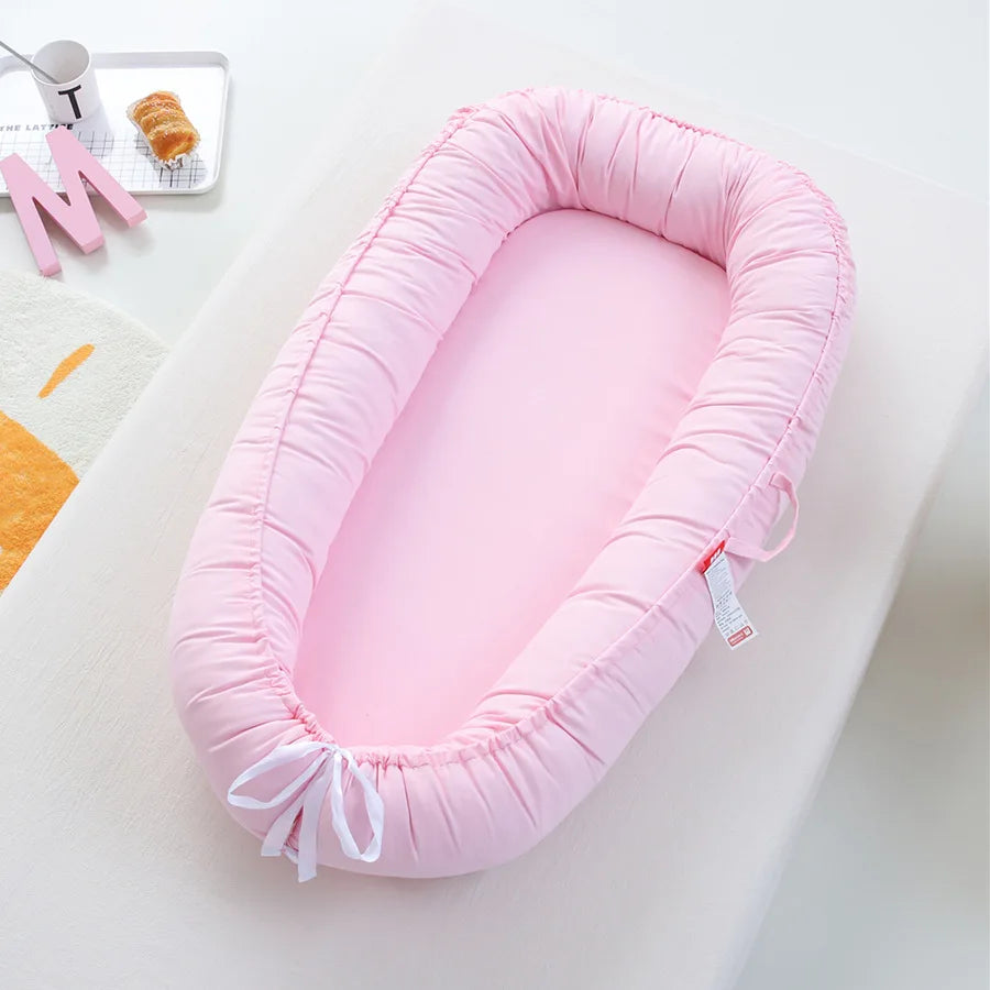 Rosa babynest med avtagbar bumper för säker myspöl